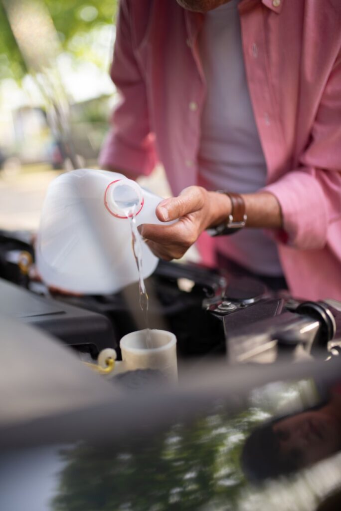 person in pink shirt putting water in a car